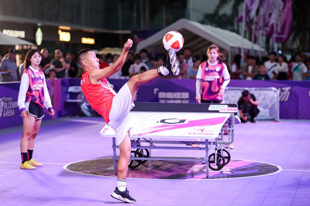 Freestyle football event on a purple arena floor with spectators